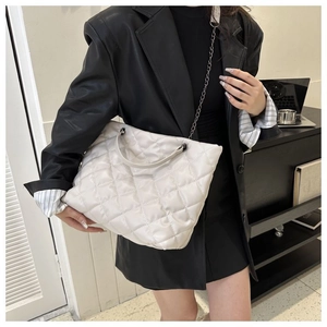 Detalle del bolso tote acolchado blanco con cadena metálica y textura de piel sintética