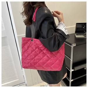 Detalle del bolso tote acolchado rosa con textura de rombos y correa de cadena