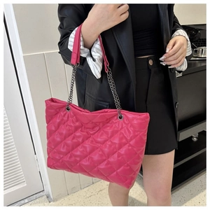 Detalle de bolso tote acolchado fucsia con correa de cadena plateada sobre el hombro