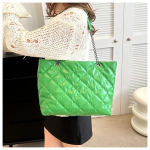 Detalle del bolso tote acolchado verde vibrante con cadena plateada y textura de cuero PU