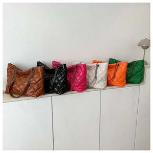 Bolsos tote acolchados de varios colores con correas de cadena en un entorno minimalista