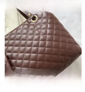 Detail of dark brown quilted tote bag with diamond stitching and gold ring hardware