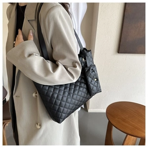 Detail of black quilted tote bag with matching pendant pouch on a wide shoulder strap