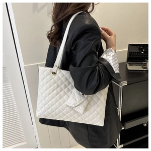 Detailed view of white quilted tote bag with matching hanging coin purse and gold hardware