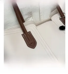 Detail view of lychee pattern cream leather tote bag with brown handles and stitching