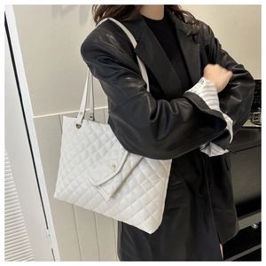 Side view of white quilted tote bag with gold buckle on model in black leather jacket