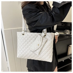 Detailed shot of white quilted tote bag with matching pouch in office setting