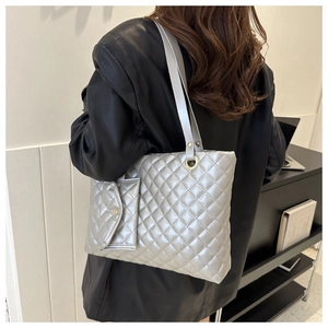 Detail of silver quilted tote bag with matching pouch on model in a modern room
