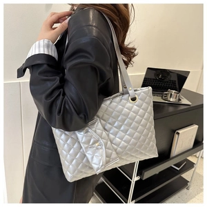 Detail of silver quilted tote bag with metallic finish and matching mini pouch on a model