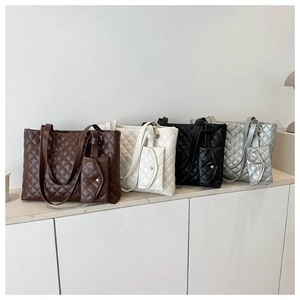 Detail view of four large quilted tote bags in brown, ivory, black, and silver grey finishes