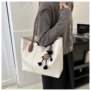 Detail of off-white tote bag with dark brown straps and cute plush lamb charm