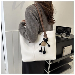 Detail of white leather tote bag with brown straps and cute sheep plush charm accessory