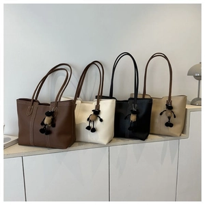Detail of four colorful leather tote bags with contrast stitching and plush sheep charms