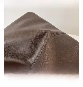 Detailed macro shot of dark brown lychee pattern faux leather texture on the tote bag