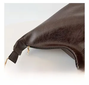 Close-up of smooth gold-tone zipper and precision stitching on dark brown leather bag