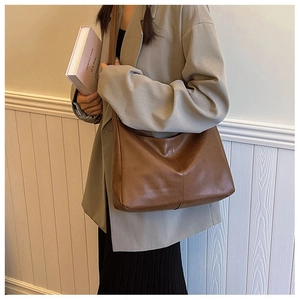Close-up of brown faux leather tote bag with wide strap and decorative stitching