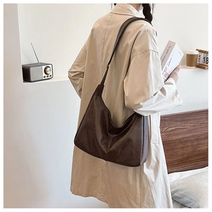 Detail view of large dark brown leather tote bag worn as a hobo shoulder bag