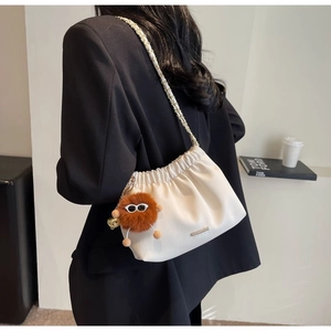 Detail of off-white pleated leather bucket bag with gold metal trim and chain strap
