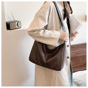 Dark brown faux leather hobo bag styled with a beige trench coat in a minimalist room