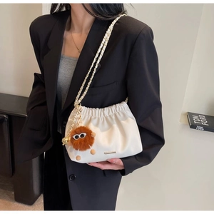 Detail of off-white pleated cloud bag with gold chain strap and brown plush monster charm