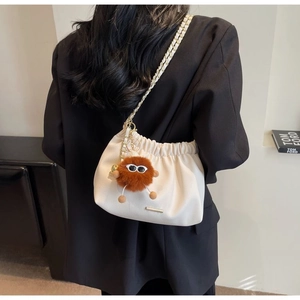 Detail view of cream leather bucket bag with gold chain and plush monster charm
