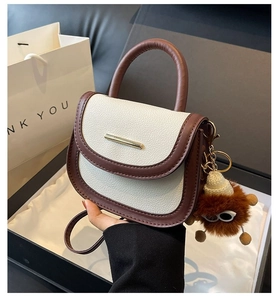Detail of color-block saddle bag with lychee texture and plush monster keychain charm