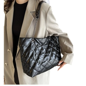 Bolso tote acolchado negro con correa de cadena mostrado en modelo para uso de diario