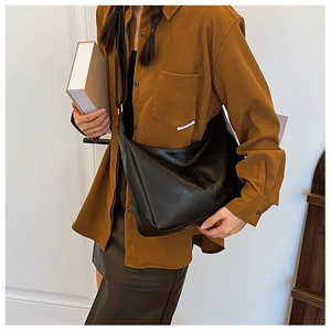 Detailed view of a large black faux leather hobo bag worn crossbody for daily style