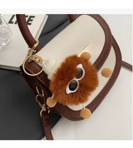Detail of color-block saddle bag featuring a whimsical brown plush monster pendant