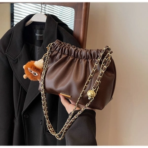 Detail of dark brown cloud bag with lychee texture and lion plush charm decoration
