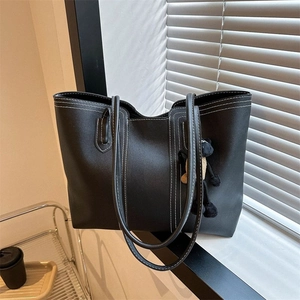 Chic black tote bag with white contrast stitching and plush bear charm for daily commute
