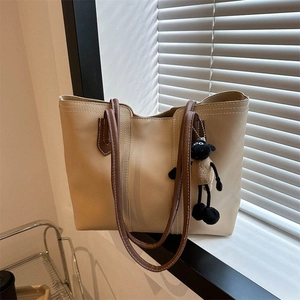 Minimalist large khaki tote bag with sheep charm displayed near a sunlit window