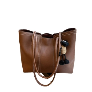 Brown leather tote bag with white contrast stitching and a cute sheep plush pendant