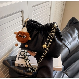 Detail of black pleated cloud bag with gold chain strap and cute plush charm pendant