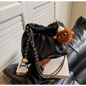 Detail of black pleated cloud bag with gold chain strap and orange monster charm