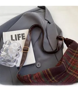 Detail of adjustable dark brown leather strap with gold metal buckle on plaid tote bag