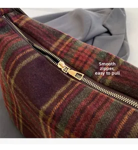 Detail of smooth gold zipper on vintage plaid wool tote bag with soft fabric texture