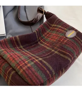 Detail of vintage plaid wool tote bag showing red and green fabric with leather logo