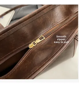 Close-up of smooth gold metal zipper on vintage dark brown lychee textured leather tote
