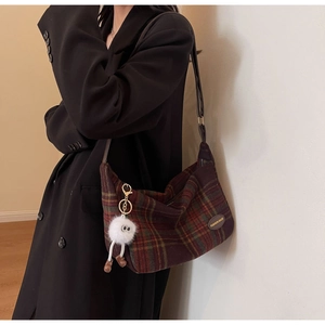 Detail of vintage plaid wool tote bag with leather strap and plush monster charm