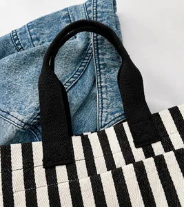 Detail of durable black woven handles on a striped canvas tote bag with textured fabric