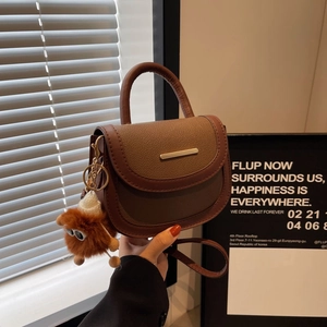 Modern color-block saddle bag in brown leather texture with cute plush monster charm