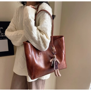 Close-up of caramel brown vintage tote bag with rabbit charm and gold hardware detail