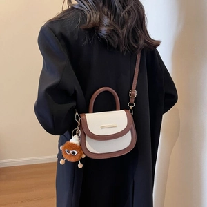 Retro two-tone saddle bag with lychee texture and plush charm in a crossbody view