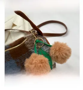 Detailed macro view of plaid wool bag with cherry pom-pom charm and metal zipper