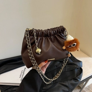 Deep brown pleated bucket bag with gold chain strap and cute plush monster charm