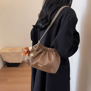 Brown cloud-style chain bucket bag with plush monster charm and pleated detail