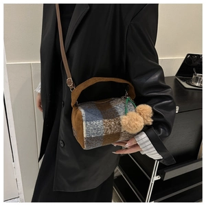 Detail of plaid wool cylinder bag with brown corduroy accents and double pompom charm