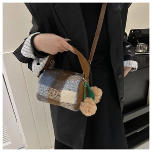 Detail of checkered plush cylinder bag with brown corduroy handle and pompom charms