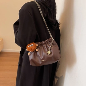 Chic brown ruched cloud bucket bag with gold chain strap and cute monster charm